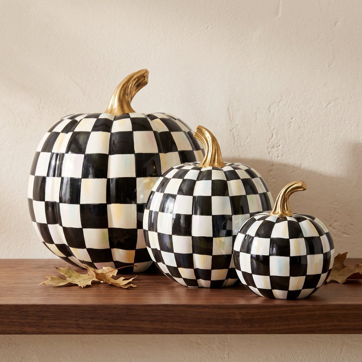 MacKenzie-Childs Courtly Check Glossy pumpkins in Medium, Small and Mini sizes grouped on a mantel, showing the obvious size steps that make a three-piece cluster read as deliberate