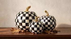 MacKenzie-Childs Courtly Check Glossy pumpkins in Medium, Small and Mini grouped together at the centre of a walnut console table, showing how the three sizes step down within one cluster