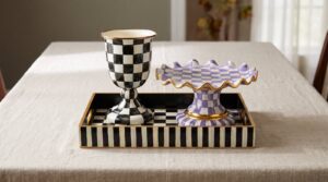 A MacKenzie-Childs Courtly Check pedestal vase and a Plum Check fluted cake stand grouped on a Courtly Check serving tray on a linen-covered fall dining table.