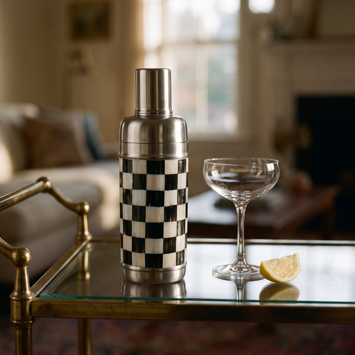 Courtly Check 3260 cocktail shaker with a stainless steel cap standing on a glass bar cart beside an empty coupe and a lemon wedge