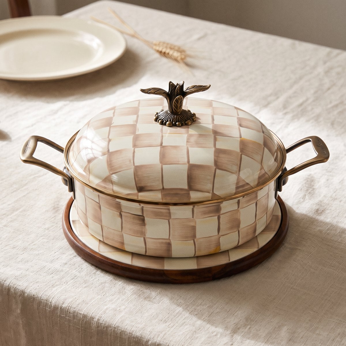 MacKenzie-Childs Mocha Check 5 qt casserole on a round trivet on a linen-covered table